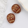Macro detail of amber Czech glass skull beads with gold-etched patterns for jewelry - Transparent Coffee