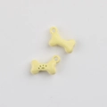 Close-up of cream bone-shaped alloy pendants with paw print for DIY jewelry making - Yellow