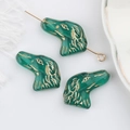 Dettaglio macro di perline di vetro verde smeraldo a forma di cane per gioielli DIY - Ciano