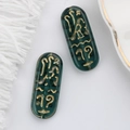Macro view of dark green Czech glass beads with gold Egyptian rune patterns for DIY jewelry - Dark Green