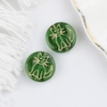 Macro detail of dark green Czech glass beads with gold painted cat design for DIY crafts - Grass Green