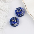 Macro shot of blue translucent glass beads with gold-painted cat motifs for DIY jewelry - Blue