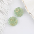 Macro shot of green Czech glass beads with gold cat engraving for jewelry making - Light Green