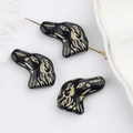 Dettaglio macro di perline a forma di cane in vetro ceco con linee dorate per DIY - Nero