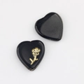 Macro shot of two heart-shaped black glass beads with golden floral relief for DIY jewelry - Black