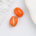 Detailed macro view of orange oval glass beads with gold painted coffee bean texture - Orange (00142801)