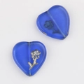 Macro detail of heart-shaped blue glass beads with gold floral engraving for DIY jewelry - Blue