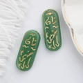 Detail of dark green glass charms with golden Egyptian rune engravings for DIY jewelry - Verdant