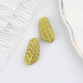 Close-up of olive green Czech glass leaf beads with gold-painted veins for jewelry making - Yellow (00590901)