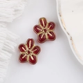 Makro-Detail von rot-goldenen fünfblättrigen Glasblumen-Perlen für DIY-Schmuck - Transparentes Rot