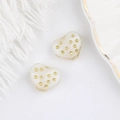 Dettaglio macro di perle di vetro a forma di cuore crema con pois dorati per gioielli - Bianco