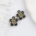 Macro shot of two vintage black five-petal glass beads with gold-rimmed detailing for DIY - Black