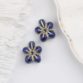 Macro shot of blue five-petal glass beads with gold accents for DIY jewelry making - Blue