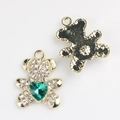Détail de pendentifs ours dorés avec strass blancs et une pierre de cœur verte - Or Vert