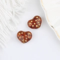 Dettaglio macro di perle di vetro a cuore ambra con pois dorati per gioielli DIY - Marrone