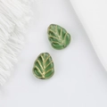 Detailed view of two 10x8mm Czech glass green leaf beads with gold gilded vein patterns - Verdant