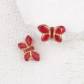 Gros plan de perles papillon en verre rouge avec bordure dorée sur un socle blanc - Rouge Transparent (00630501)