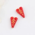 Macro shot of red heart-shaped Czech glass beads with vintage gold leaf pattern details - Red