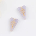 Close-up of lavender heart-shaped glass beads with vintage gold leaf vein patterns - Purple