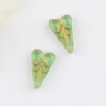 Macro detail of heart-shaped green glass beads with hand-painted gold leaf patterns - Transparent Light Green