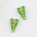 Macro view of green heart-shaped Czech glass beads with gold leaf patterns for DIY jewelry - Transparent Grass Green