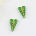 Close-up of translucent green leaf-shaped glass beads with gold-leaf patterns on white - Transparent Green