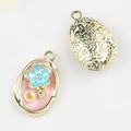 Detail showing pink enamel floral pendant with blue flower, pearl, and star-textured back - Gold Base Pink Flower