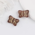 Macro detail of vintage Czech glass butterfly beads with gold gilded patterns for DIY jewelry - Amethyst