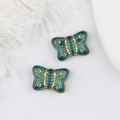 Macro shot of dark green Czech glass butterfly beads with detailed gold leaf gilding - Dark Green