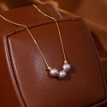 Elegante collar de cadena dorada con tres perlas malva sobre un estuche de cuero de lujo - Perla Artificial Morado Claro (XL3862) / Chapado en oro 18K
