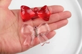 Detailed view of clear red and pink resin bow charms held by hand for scale and texture - 41*31mm / Random Mix