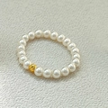 Elastic pearl ring with a single engraved gold bead on light grey textured background - Small Bead Style