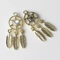 Close-up of golden dreamcatcher charms with heart rhinestones and feather pendants - Gold Base White