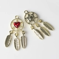 Macro view of golden dreamcatcher pendant featuring a red heart stone and feather charms - Gold Base Red