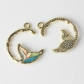 Macro detail of alloy fishtail charms showing enamel finish and textured metal back - Gold