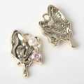 Macro detail of golden butterfly charms with pearls and pink heart-shaped crystals - Gold / Pink