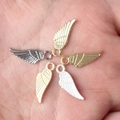 Five assorted alloy wing charms for DIY jewelry held in hand to show the actual small size - Random Mix
