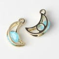 Macro detail of moon-shaped alloy pendants with light blue zircon and golden plating - Gold Base Blue