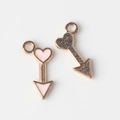 Detailed macro of pink enamel arrow-heart charms with rose gold metal texture - Pink