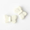 Macro detail of cream white butterfly charms with dot texture and hole for DIY jewelry - White