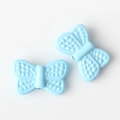 Macro shot of light blue bow pendants with textured surface and threading hole for DIY jewelry - Blue