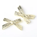 Close-up of golden bow-shaped metal charms with intricate diamond embossing for DIY jewelry - Gold