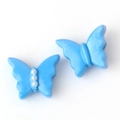 Detalle macro de dijes de mariposa azul con perlas blancas para joyería artesanal - Azul