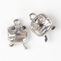 Close-up of two silver monster-shaped pendants with black eyes and dual hanging loops - Silver