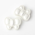 Detail view of two pearl white bow beads with beaded edges and threading holes for DIY - White