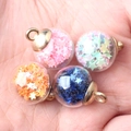 Handheld view of four colorful star-filled glass ball pendants for DIY jewelry making - Multicolor (Random Mix)