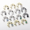 Detailed view of C-shaped metal pendants with lava texture and colored zircon stones - Random Mixed