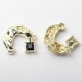 Macro shot of gold alloy C-shape pendant with lava texture and black square gemstone - Black/Gold Base