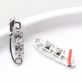 Dettaglio di orecchini argentati con zirconi quadrati su un bordo di ceramica bianca - Silver Base White Rhinestone