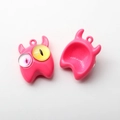 Nahaufnahme von rosa kleinen Monster-Anhängern mit bunten Augen für DIY-Schmuckherstellung - Hellrosa